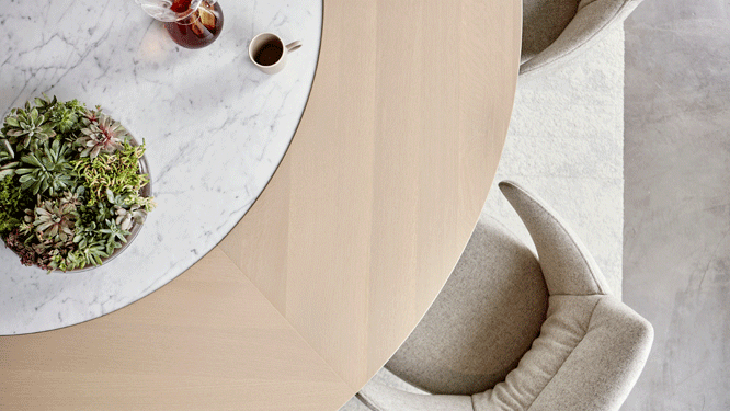 Top view of round wooden conference table with marble center and light grey lounge office chair.