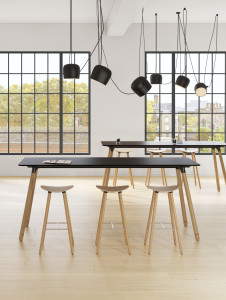 Cafe space in office with long black meeting tables, hanging black lamps, and wooden stools
