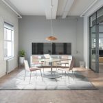 Quiet office conference area with cushioned seating, plush grey rug, and dual monitors mounted to wall