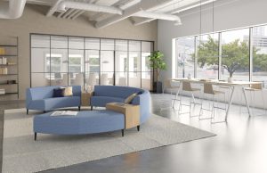 Blue round office sectional couch with white rug and nearby cafe-height table in office lounge setting