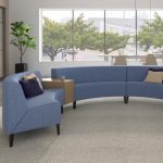 collaborative space with a blue circa lounge system with wooden small tables. Behind we can see lounge chairs, collaborative tables and stools.
