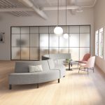 Lounge space in office with connected grey sectional couch, round side table, and pink side chairs