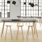 Long grey office conference table with wooden legs and matching stools in front of an arched window