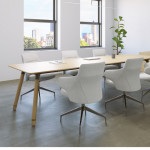 Long wooden conference table with white conference chairs, matching armrest, wooden storage credenza, and wall-mounted monitor