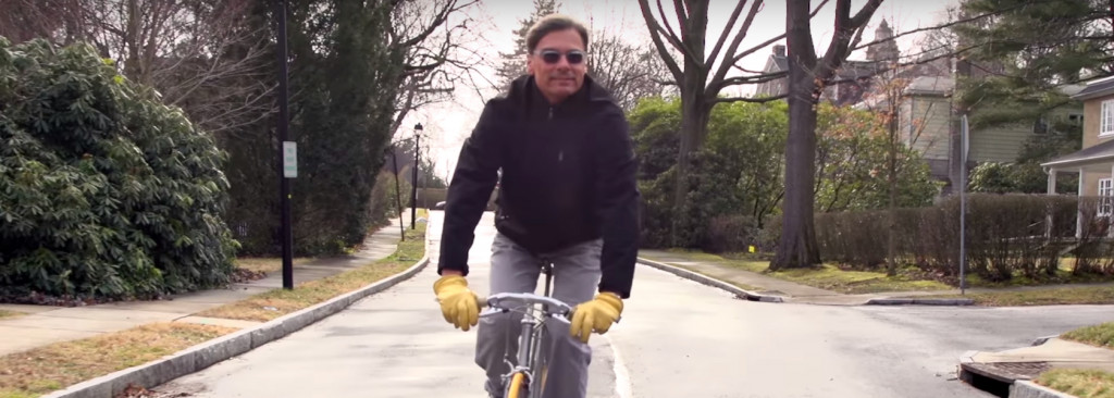 Man riding bicycle down rainy suburban road