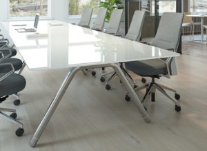 Long white glass meeting room table with grey mobile office chairs on either side