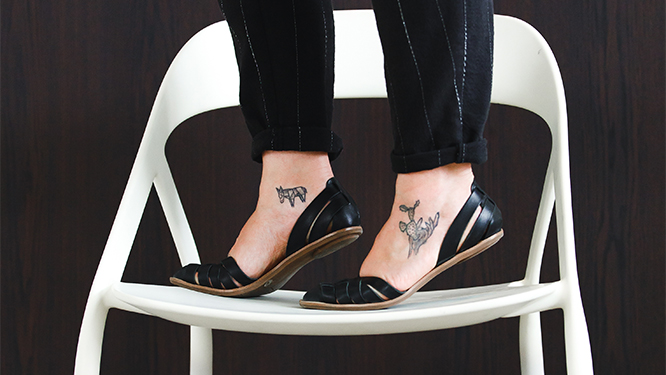 Woman with a small tattoo on each foot standing on a white carbon fiber chair.
