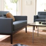 Dark blue leather sofas around square wooden coffee table on orange and brown rug
