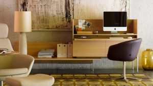 Home office with wooden desk and cabinet, brown leather office chair, matching table lamp, and iMac on desk