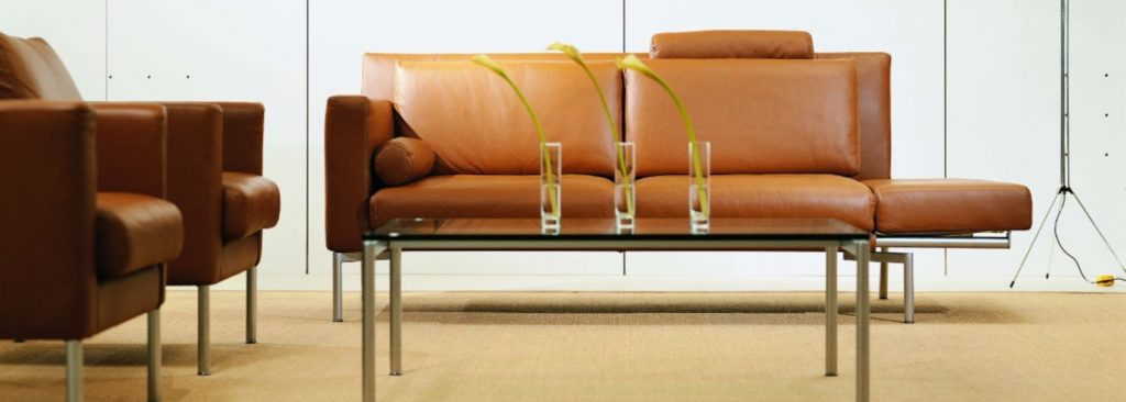Brown leather sofa with matching chairs and glass coffee table