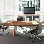 Office meeting space with plush leather chairs, grey carpeting, and long wooden conference room table
