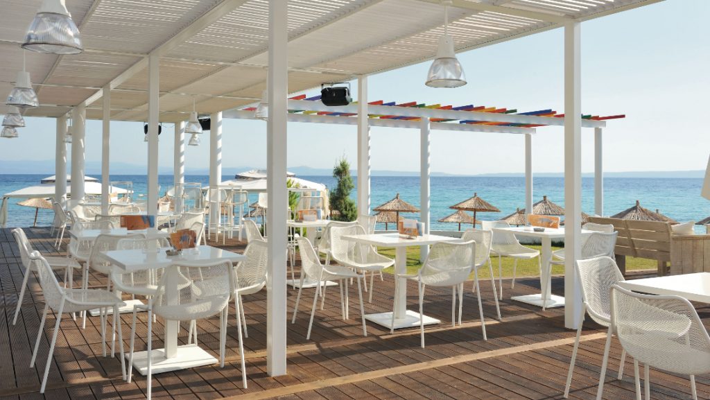 Outdoor patio area with white outdoor chairs and tables, overlooking the water
