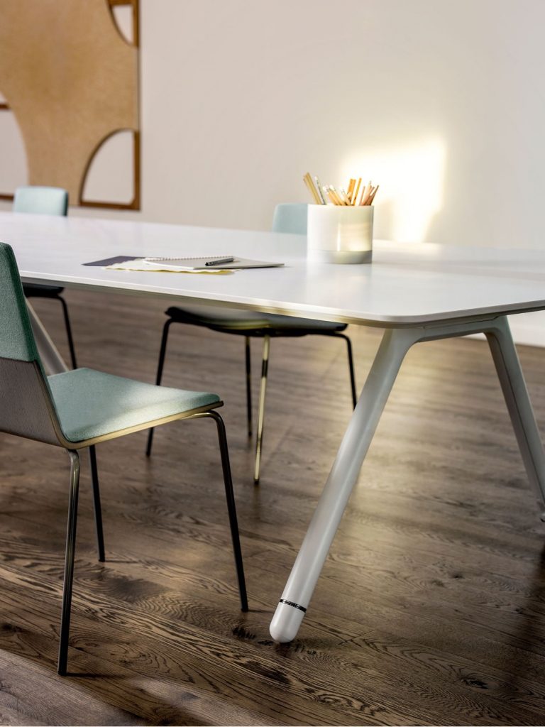 Edge of white conference table in meeting room with side chairs and pencil holder