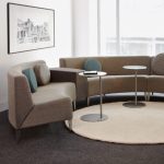 Circular grey office couch in corner of lounge space with side tables and matching bench seating
