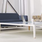 White office lounge area with blue and floral midcentury modern couches, low profile white metal table, and potted plant