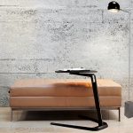 Brown leather bench seat in office lounge with side work table and exposed brick wall