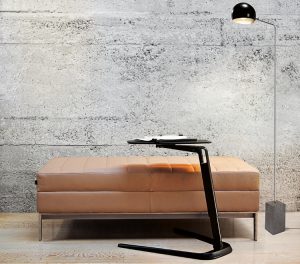 Brown leather bench seat in office lounge with side work table and exposed brick wall