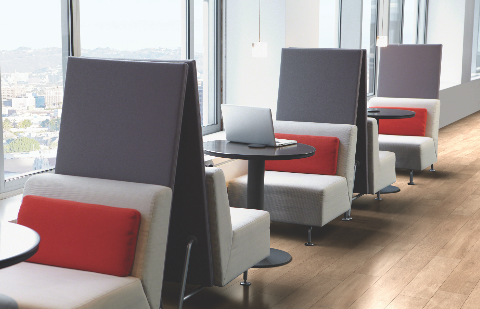 Small privacy booths in office with cushioned bench seating, circular tables, and privacy screens dividing each booth