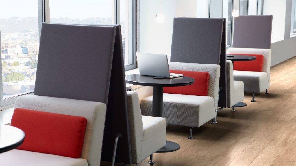 Small privacy booths in office with cushioned bench seating, circular tables, and privacy screens dividing each booth