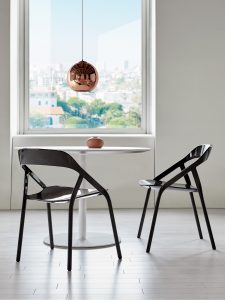 Circular side table in office cafe with black carbon fiber side chairs