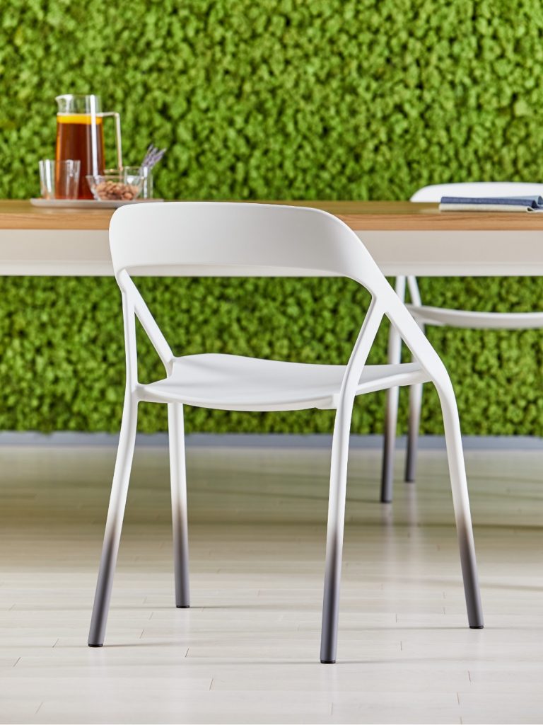 White outdoor chair near wooden outdoor table and ivy covered wall