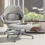 Quiet focus area in office with grey lounge chair, matching ottoman, and wooden bookcase with magazines