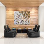 Lounge space in office with high-backed plush lounge chairs, standing lamp, and matching wooden side tables