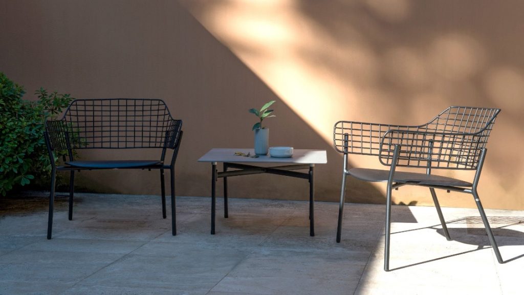 Metal wire outdoor lounge seats in yard area with table and plants nearby