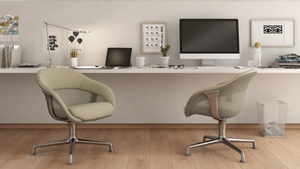 Two low back conference lounge chairs at wall mounted desk with computer and laptop