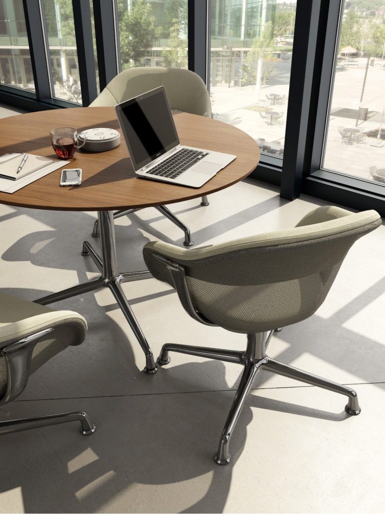Grey office chairs surrounding round wooden coffee table with device charger in center