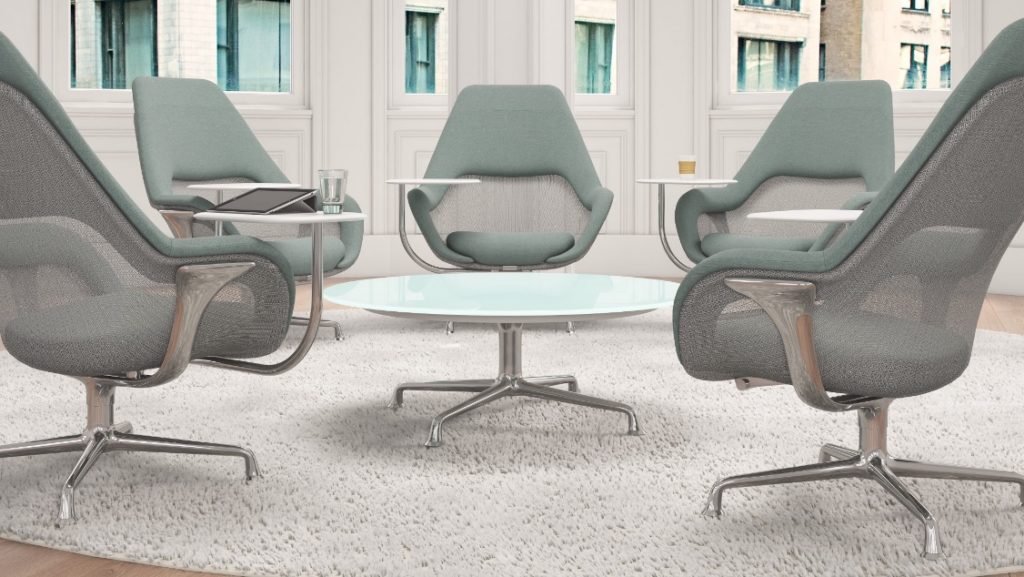 Office lounge space with green upholstered meeting chairs, round table in middle, and white outdoor rug