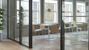 Glass door leading into office dining area with cafe height chairs and tables