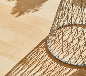 Shadow cast on wooden floor by light shining through wire base of outdoor stool