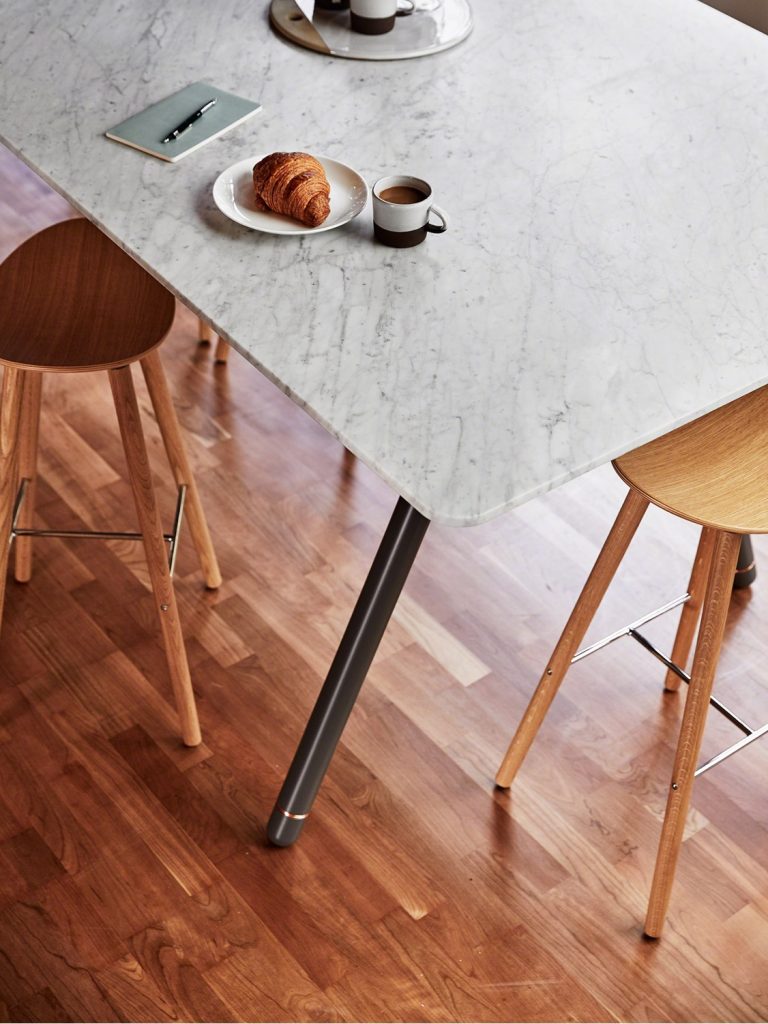 Marble table in office cafe space with wooden stools and hardwood floor