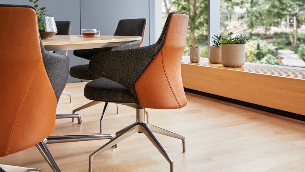 Leather and fabric conference room chair on aluminum base, facing a wooden conference table with a coffee cup