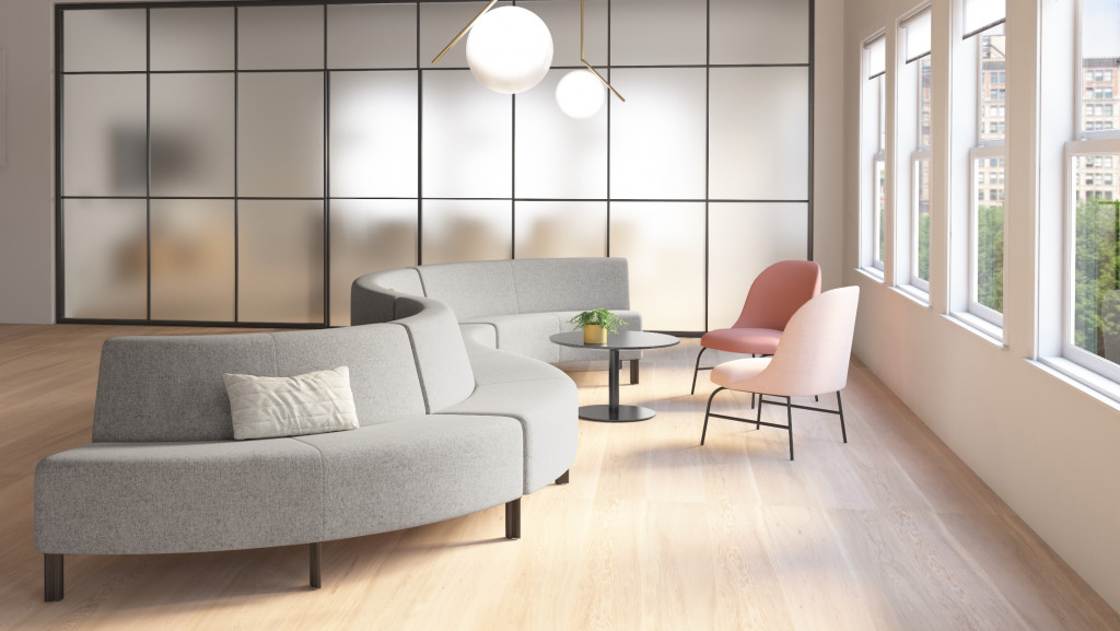Lounge space in office with connected grey sectional couch, round side table, and pink side chairs
