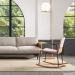 Salmon-colored office rocking chair in front of tall lamp and office couch