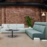 Blue office corner sofa in outdoor lounge space with mirrored black coffee table and wooden side chair