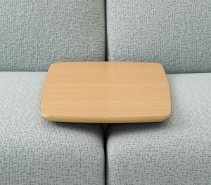 Wooden side table attached between two grey couch cushions