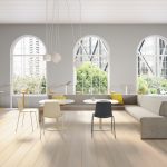 Office lounge & dining area with grey corner couch, two matching white chairs with black & white seats, and cafe tables in background
