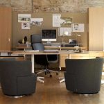 Private office with long wooden table, wooden storage cabinets, black leather executive chair, and grey armchairs