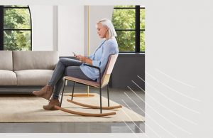 Woman sitting in office rocking chair and looking at her phone in an office lounge space