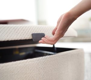 Hand using handle to open storage compartment of office storage ottoman