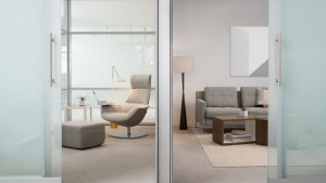 Office focus space with high-backed chair, grey couch, side tables, and frosted glass door