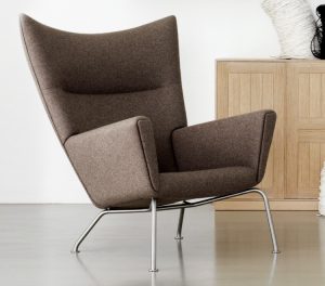 High winged-back brown upholstered lounge chair with wooden storage cabinets
