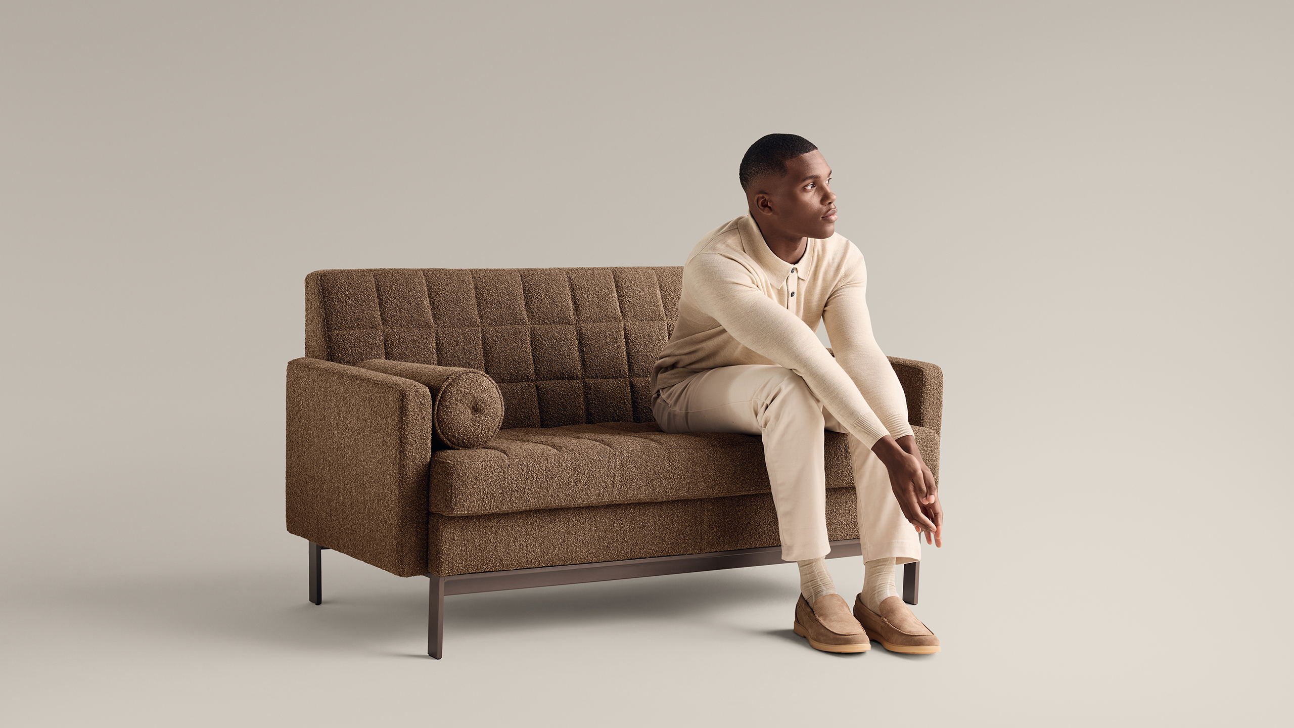 Man sitting with his arms resting on his legs on a brown Millbrae Contract sofa