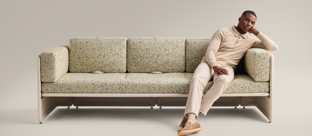 Person seated on sofa against a neutral background