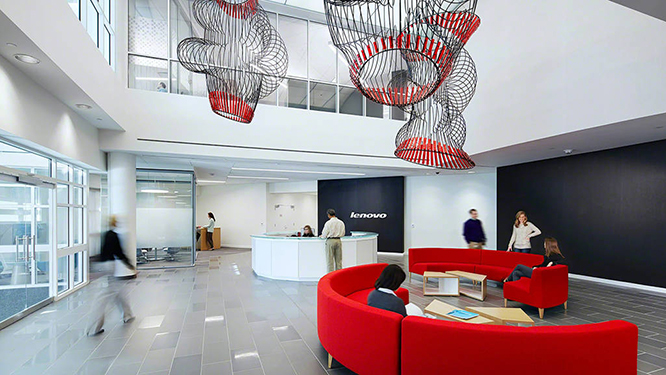 Open office area with two half round red couches, circular reception desk and hanging black and white art fixtures.
