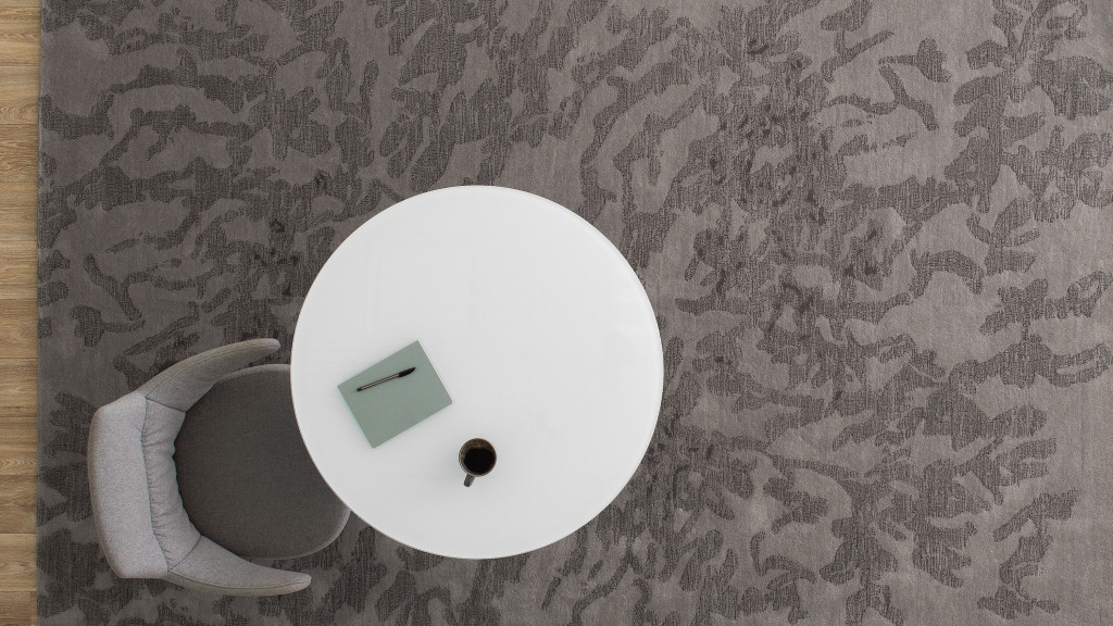 Overhead view of a gray conference chair next to a white table on a gray rug.