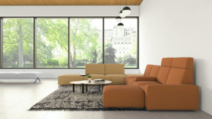 Office social space with connected brown & tan sectional couch, large patterned rug, and round nesting coffee tables